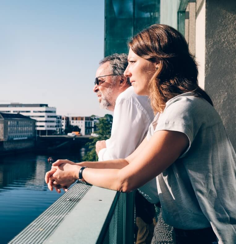 Frau und Mann über Geländer gelehnt schauen auf Fluss
