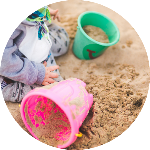 Kinderhände die im Sand mit Eimer spielen