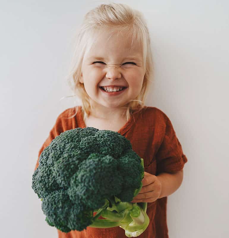 Lachendes Kind hält Broccoli